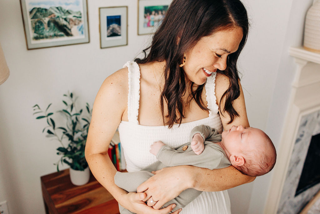 A new mom smiles down at her newborn baby in her arms