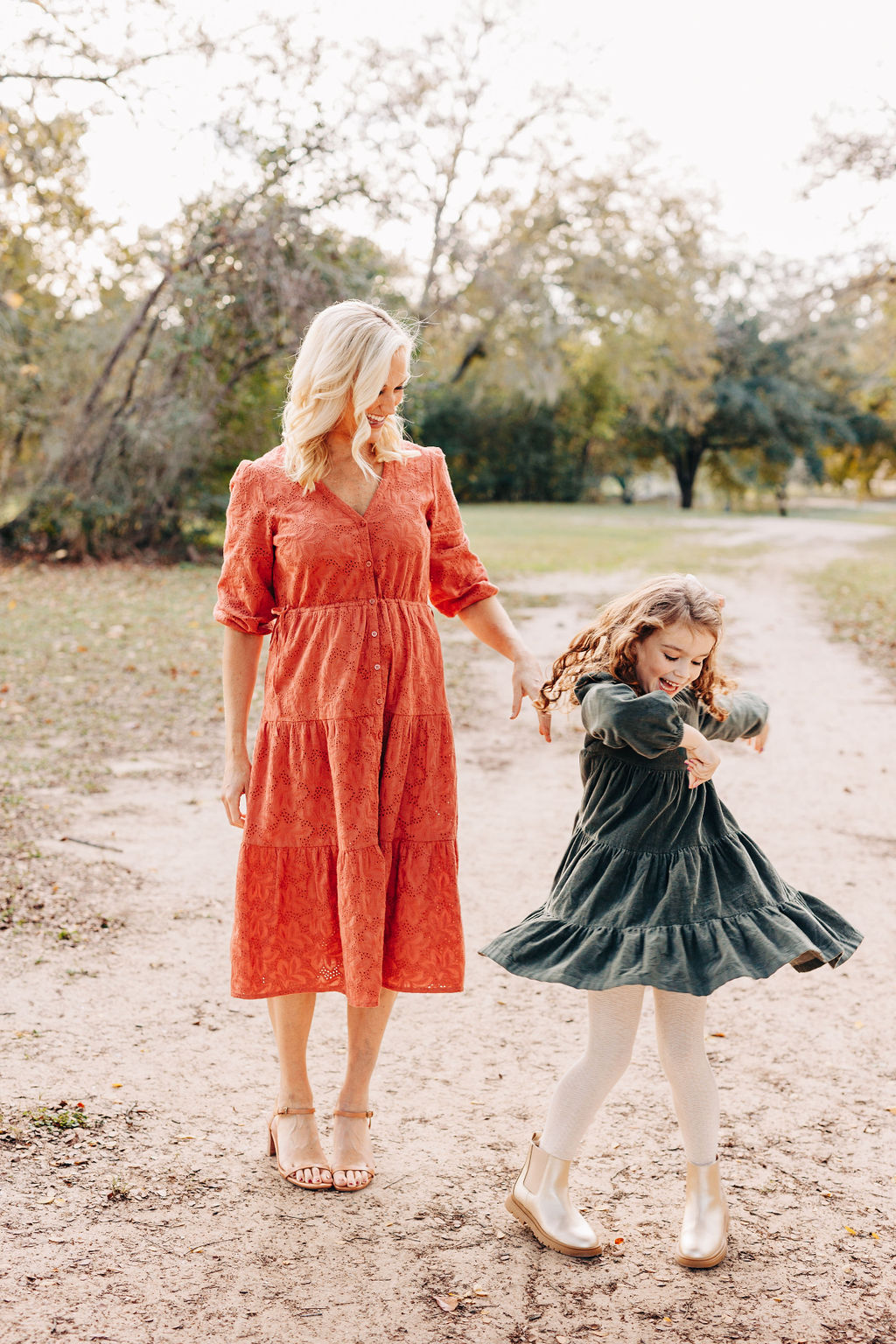 A mom dances and twirls with her toddler daughter in dresses in a park at sunset before eating at family friendly restaurants in houston
